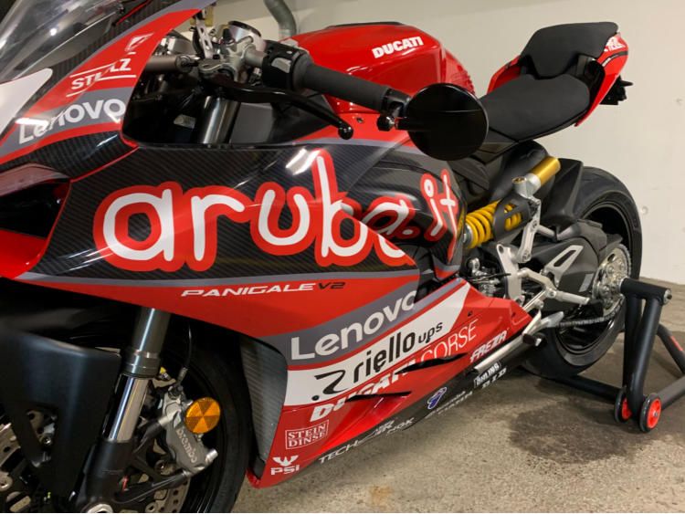 Rotes Rennmotorrad mit Sponsoren-Schriftzügen auf der Verkleidung
