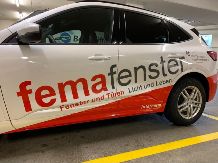 Weisser Personenwagen mit rotem Schriftzug femafenster